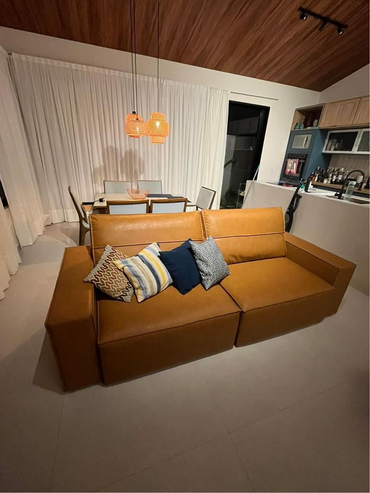 Sala da Casa R&J com sofá caramelo e pé-direito de madeira