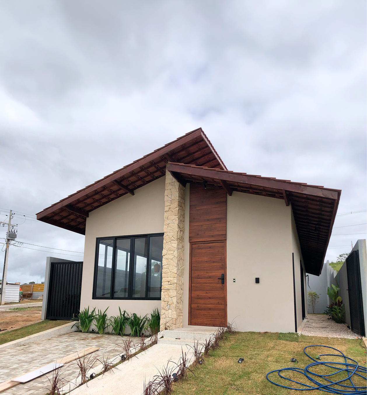 Fachada da Casa R&J de dia, com detalhes de madeira e pedra